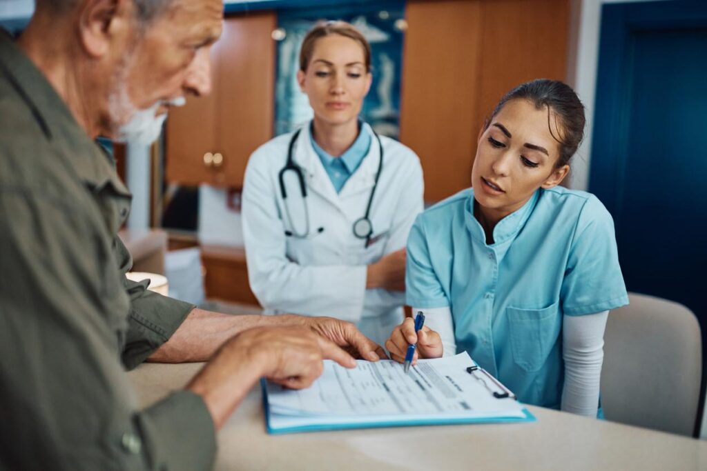 A doctor, nurse, and patient filling out forms.